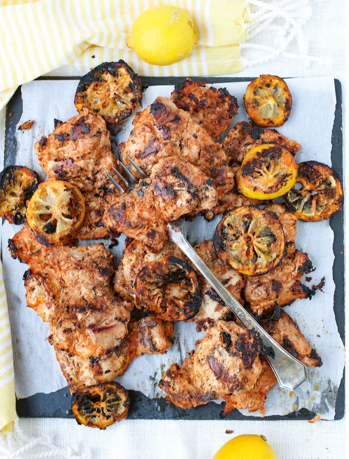 Grilled Aleppo pepper chicken and lemons on a platter