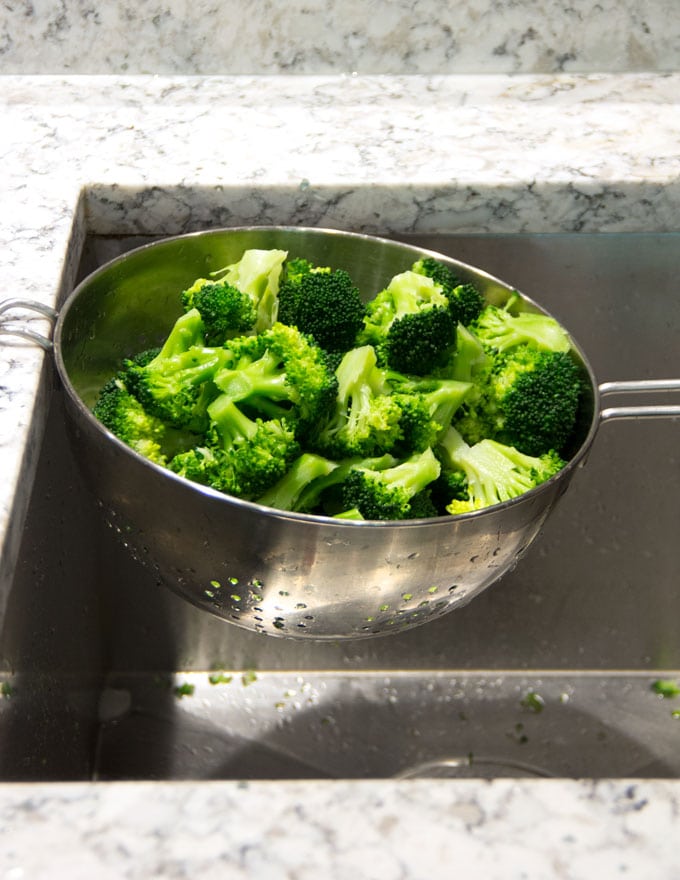 blanched broccoli florets draining in a colander 