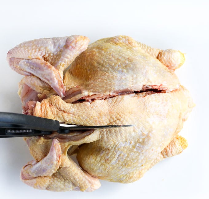 Cutting the backbone out of a whole chicken to butterfly it