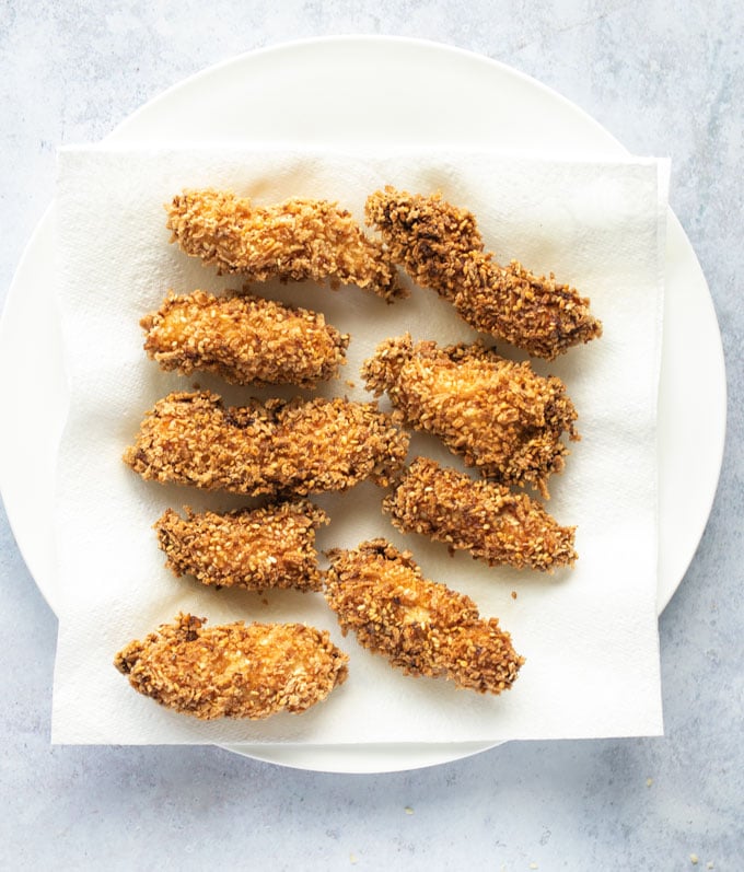 fried chicken bites draining on paper towel lined plate