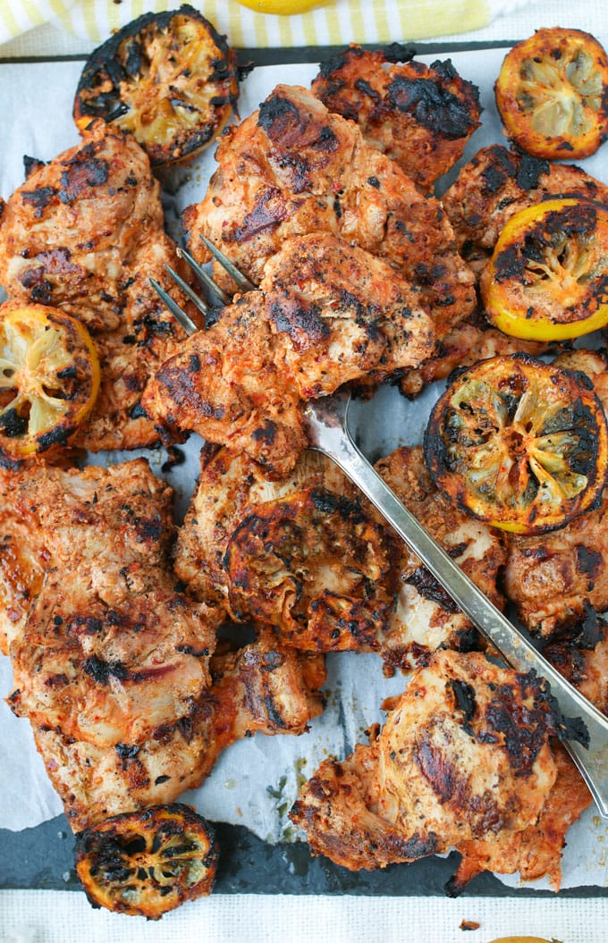 grilled Aleppo pepper chicken on a platter with grilled lemons