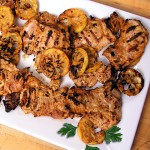 white platter topped with grilled chicken thighs and grilled lemon slices