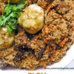 lamb and rice with carrots in a bowl with two bulbs of garlic.
