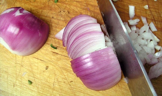 close up of a red onion being sliced into perfect dice