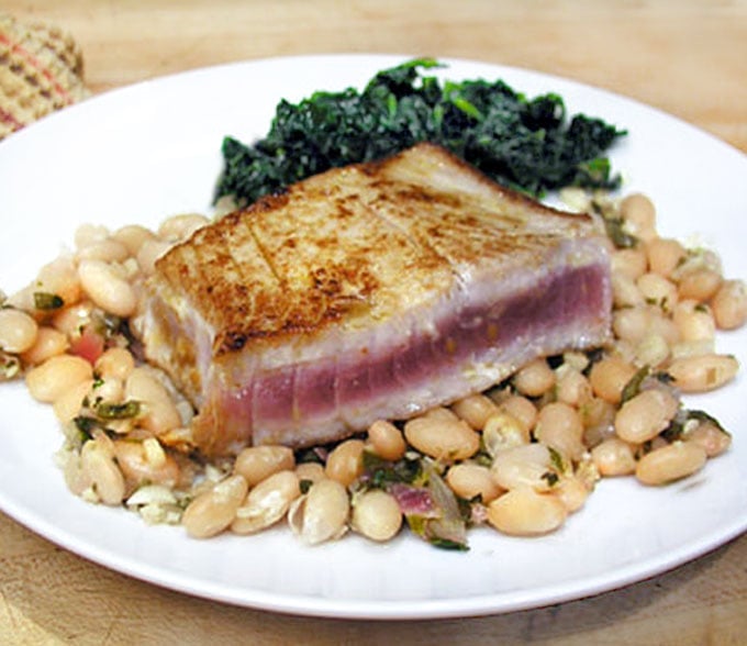 rare seared tuna stead on top of a plate of white beans 