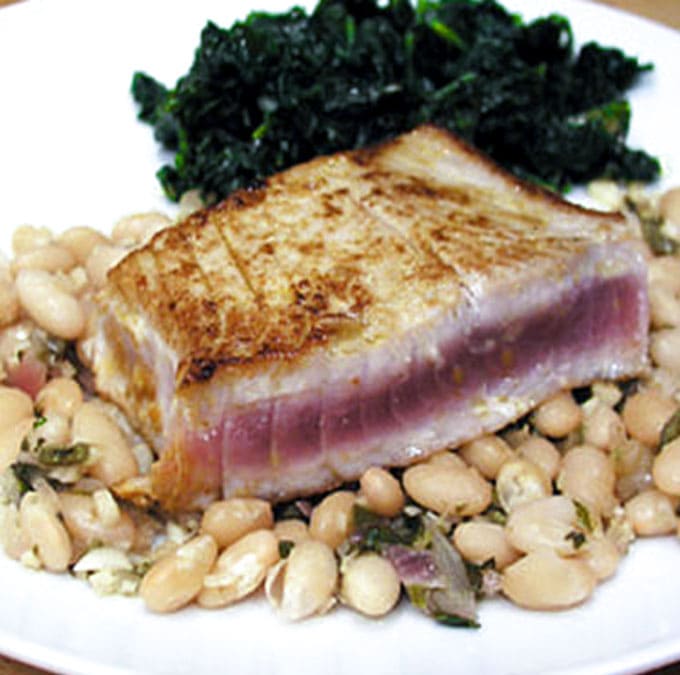 close up of a rare tuna steak, seared and on top of Peruvian white beans