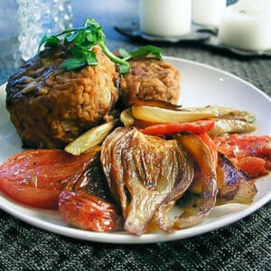 Risotto cakes on a plate with roasted fennel and roasted tomatoes