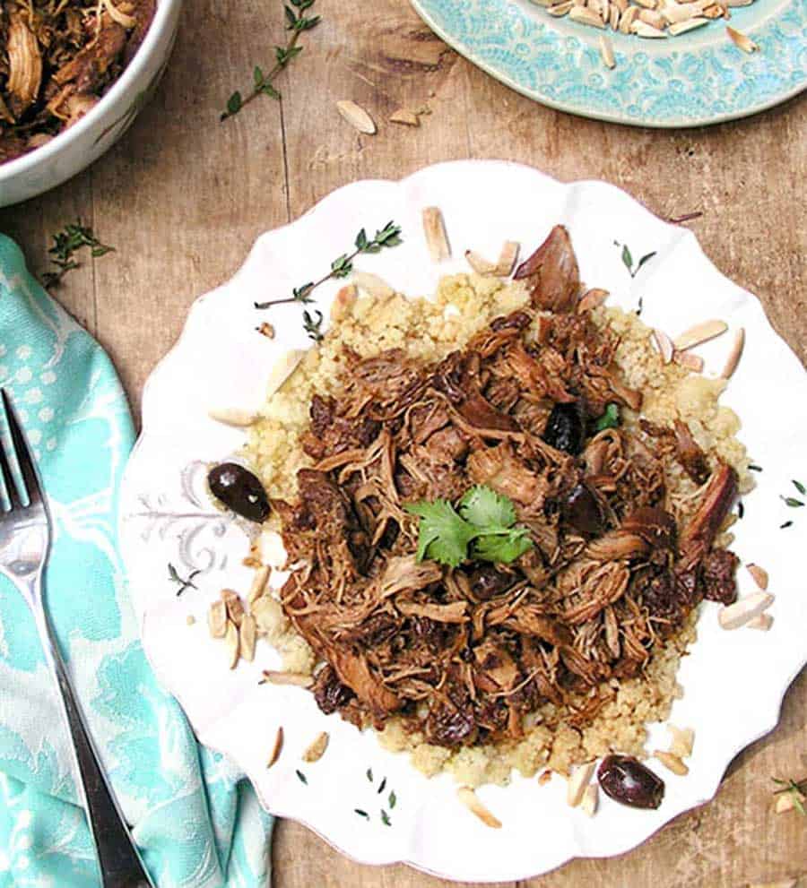 white plate topped with couscous and slow cooker chicken with dried cherries and black olives