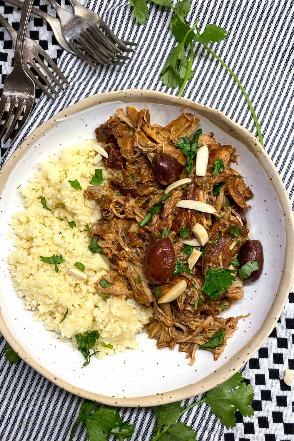 slow cooker chicken thighs and couscous in a whote bowl on a black ad white checked dishcloth