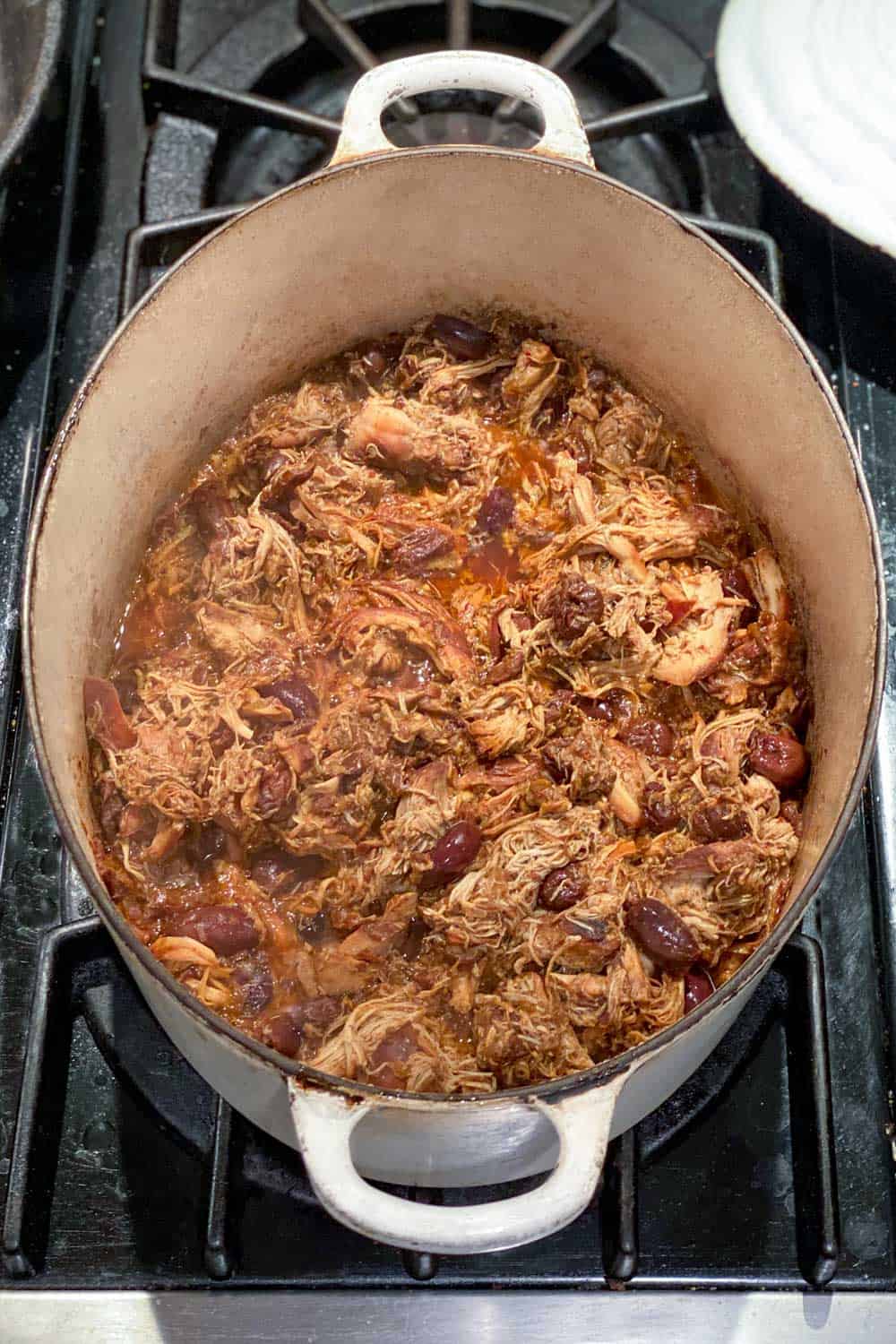 Slow cooker chicken thighs in an oval Dutch Oven, seen from above.