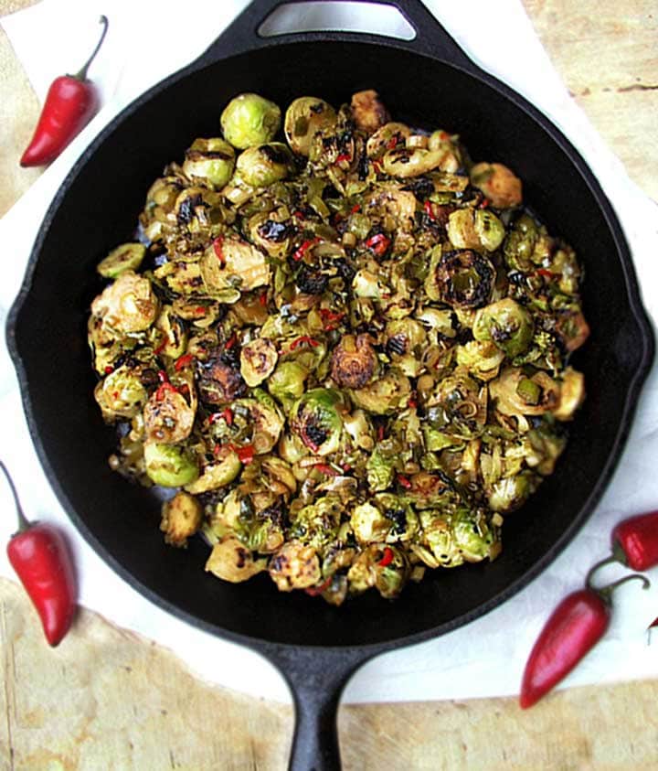 cast iron skillet with sliced, browned brussels sprouts with maple chili sauce.