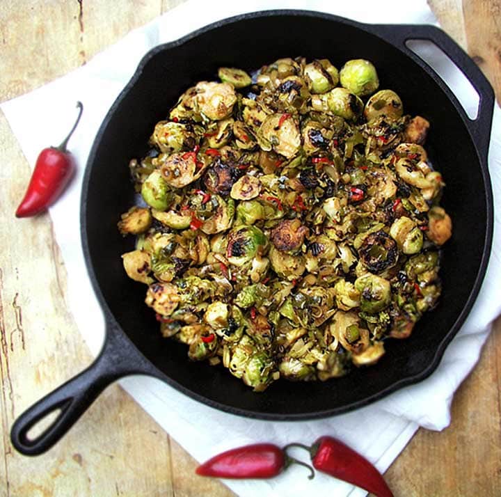 cast iron skillet with sliced, browned brussels sprouts with maple chili sauce.