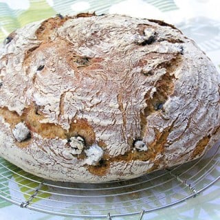 a loaf of homemade no-knead Olive bread on a cooling rack