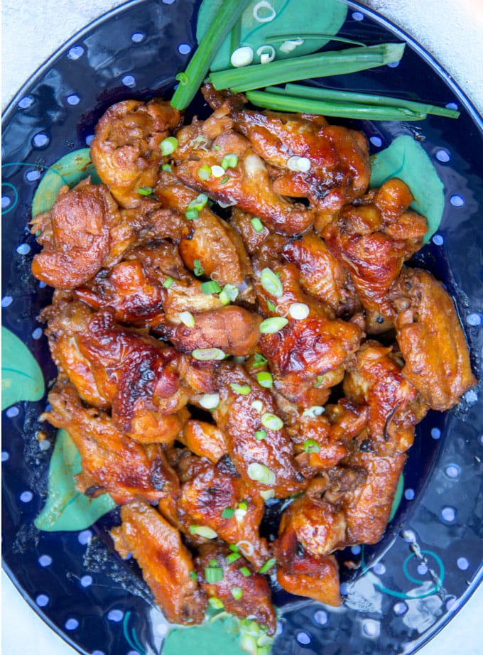 Lime apricot chicken wings on a platter with scallions