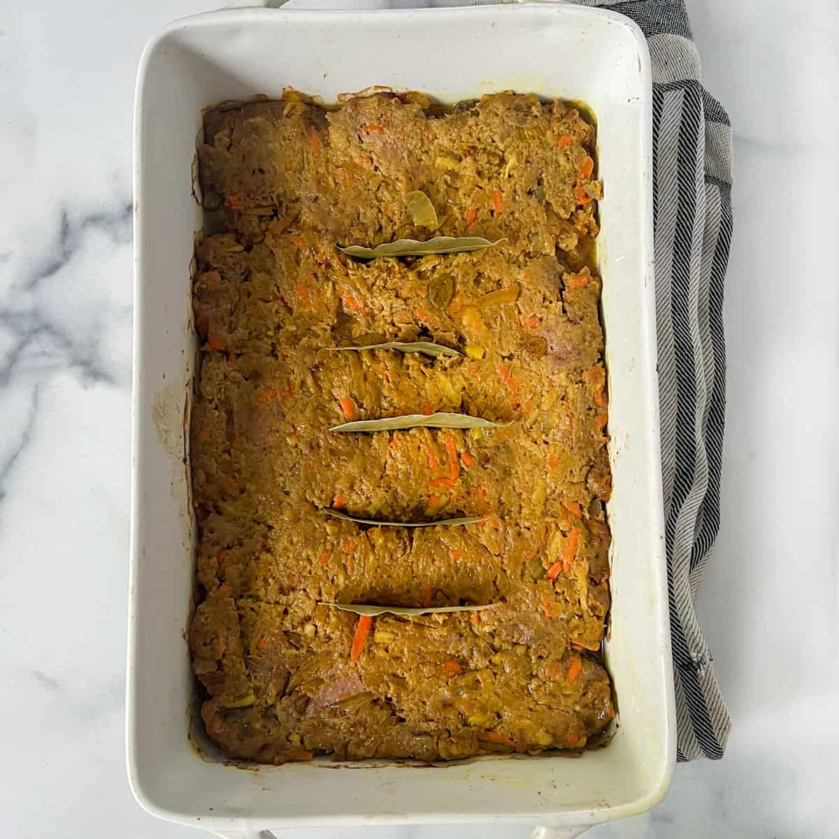 partially cooked casserole with 5 bay leaves inserted down the middle.