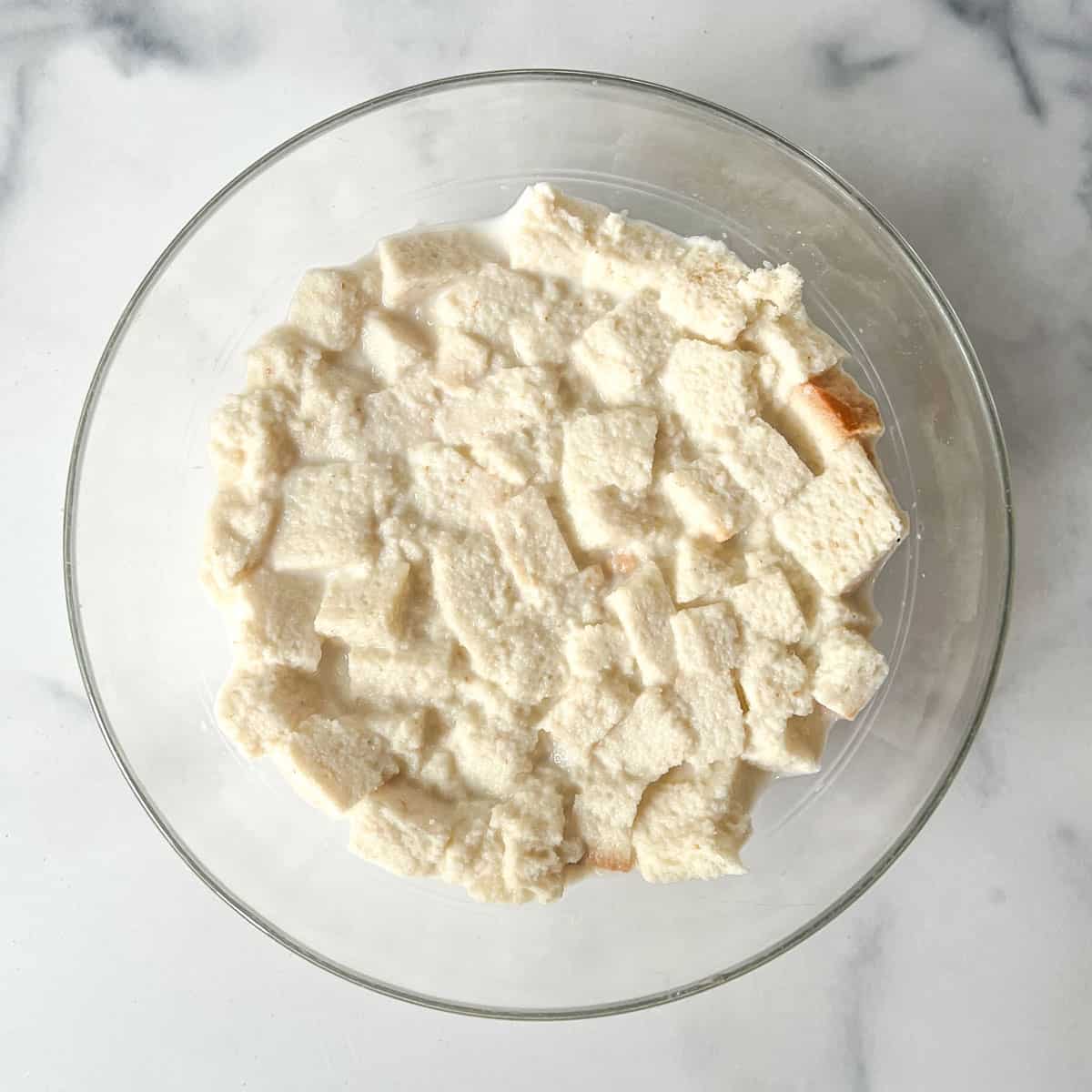 glass bowl of bread cubes soaking in milk