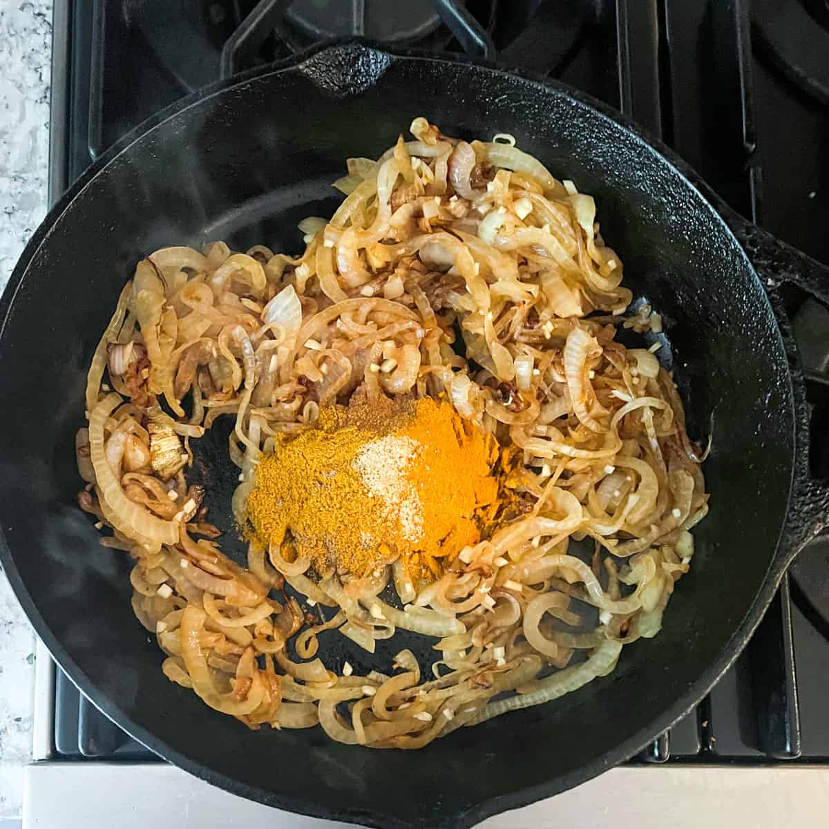 Sauteed onions and garlic in a cast iron skillet topped with ground spices.