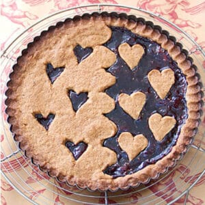 A linzertort with hearts cut out of the crust so you an see the raspberry jam come through.