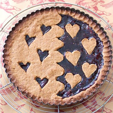 A linzertort with hearts cut out of the crust so you an see the raspberry jam come through.