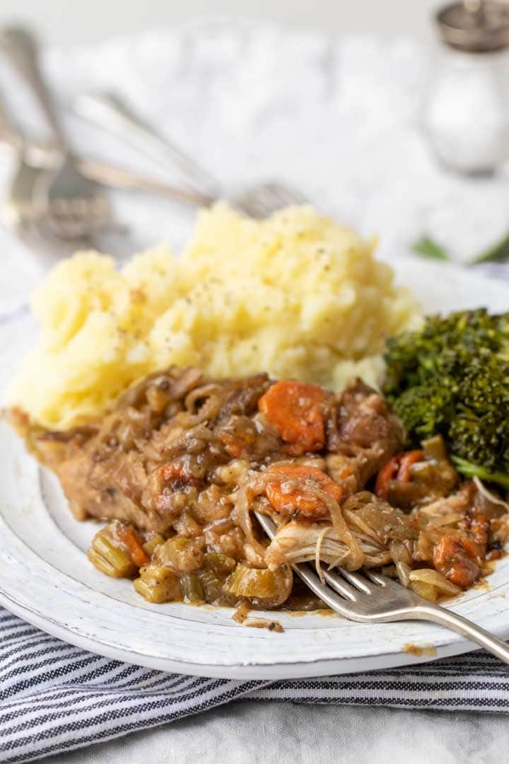 Smothered chicken on a plate with mashed potatoes and broccoli