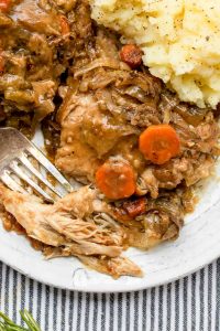 close up of smothered chicken with a fork digging in and mashed potatoes
