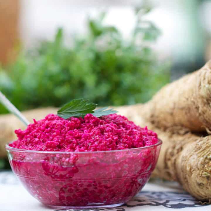 bowl of hot pink horseradish sauce and a horseradish root in the background.