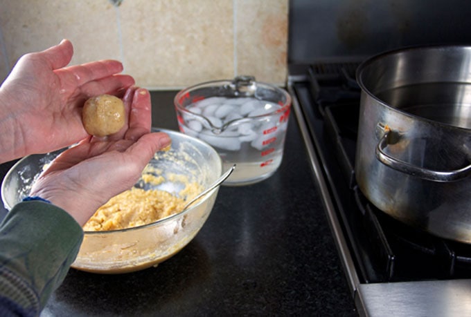 how to make matzo balls for matzo ball soup, showing hands shaping the raw matzo meal dough
