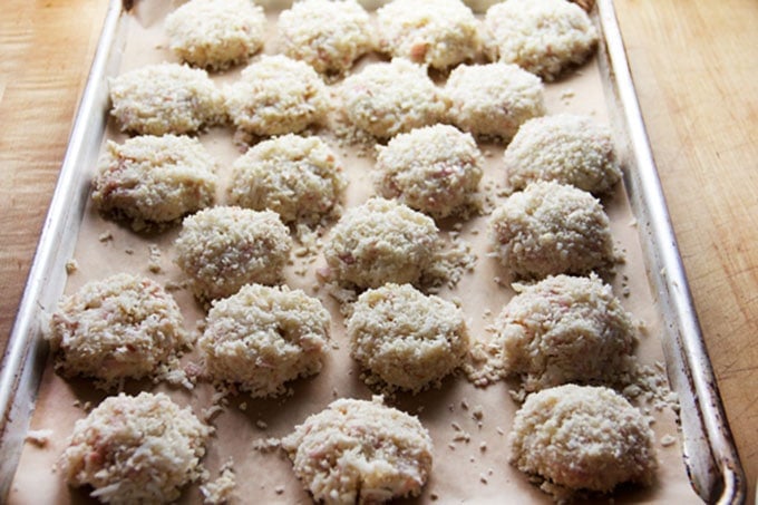 22 uncooked Royal Thai Crab Cakes on a parchment lined baking tray