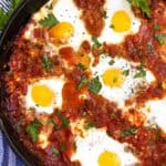 shakshuka in a cast iron skillet with parsley sprigs to garnish