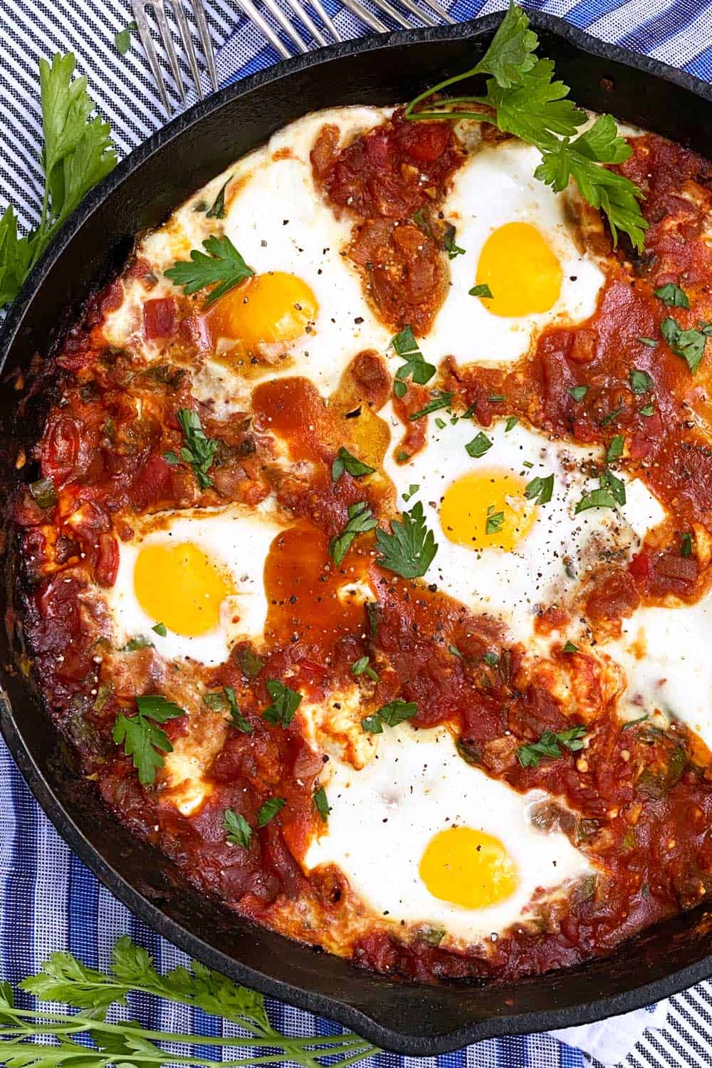 shakshuka in a cast iron skillet with parsley sprigs to garnish