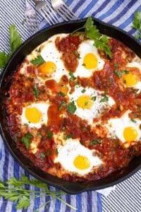 shakshuka in a cast iron skillet with parsley sprigs to garnish