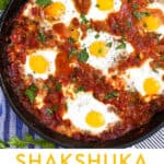 shakshuka in a cast iron skillet with 6 eggs poached in spicy tomato sauce