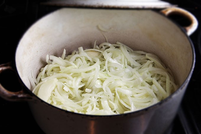 a dutch oven half-filled with sliced onions