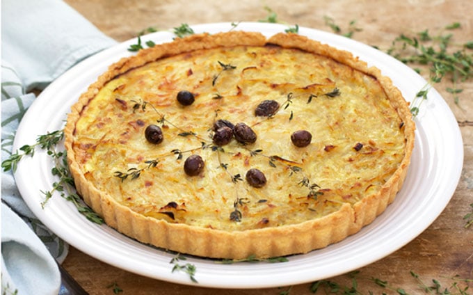 This delicious Provençal French onion tart has a 2-ingredient filling of braised onions mixed with eggs, and baked in a mustard-coated pie shell. A fantastic recipe for brunch or a Mediterranean inspired dinner l www.panningtheglobe.com 