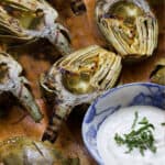 Pinterest Pin: 5 grilled artichoke halves and a bowl of lemon aioli with slivered basil in the middle