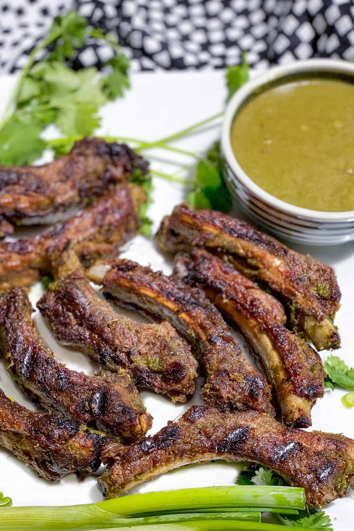 white platter with 8 Thai Coconut BBQ Ribs and a small bowl of Thai Coconut BBQ Sauce