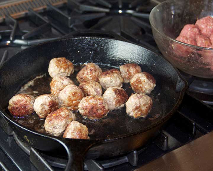 showing how to sauté lamb meatballs in a cast iron skillet to brown them