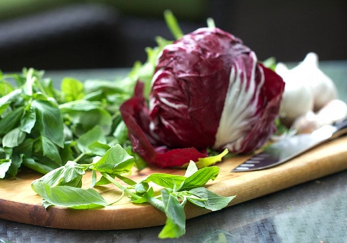 a cutting board with a head of radicchio on it and a bunch of fresh basil