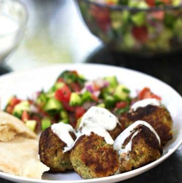 5 turkey falafel meatballs on a plate, drizzled with yogurt sauce