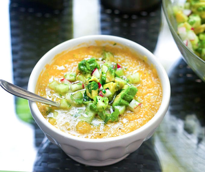 This Gazpacho can be made with yellow or red tomatoes. Serve it icy cold with the delicious topping of chopped cucumbers, radishes and avocados. The quintessential summer soup recipe l www.panningtheglobe.com 