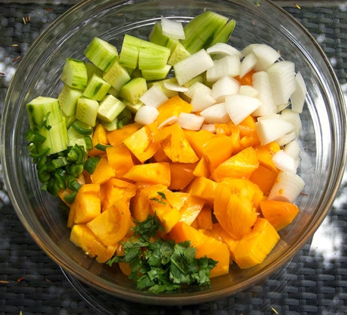 This Gazpacho can be made with yellow or red tomatoes. Serve it icy cold with the delicious topping of chopped cucumbers, radishes and avocados. The quintessential summer soup recipe l www.panningtheglobe.com 