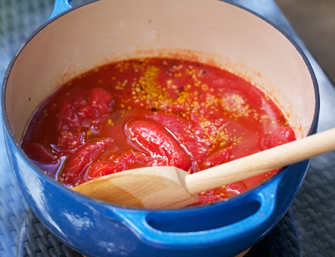 How to make homemade tomato sauce: a pot of plum tomatoes and other ingredients.