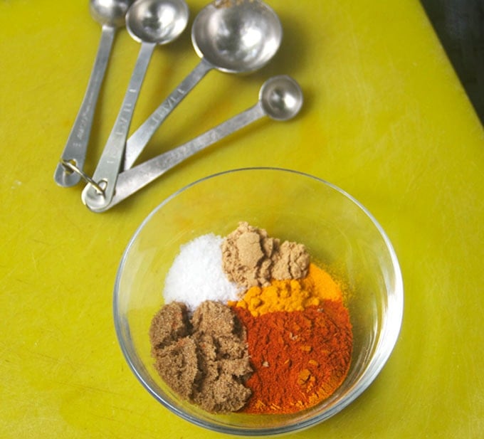 photo shows how to make Indonesian sate spice mix with give different spices in a bowl and measuring spoons.