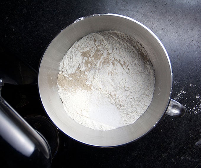 Flour, yeast, sugar and salt in the metal bowl of a stand mixer.