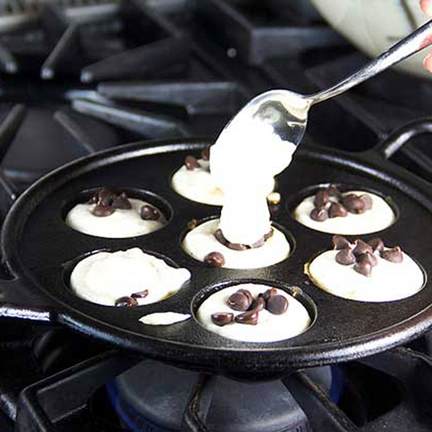 Showing how to spoon a small blob of aebleskiver batter over the filling to seal it in.