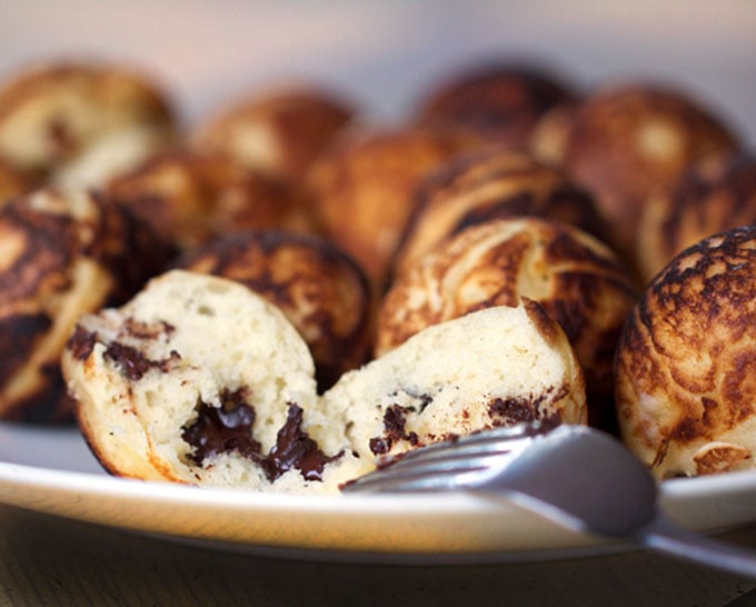 close up of a plate of aebleskiver with the one in the front cut in half, showing its chocolate filling
