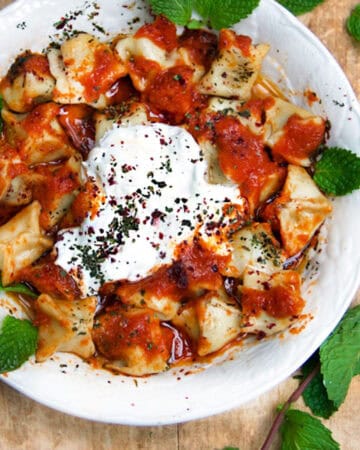 Tiny raviolis with tomato sauce, yogurt sauce and brown butter sauce and herbs.