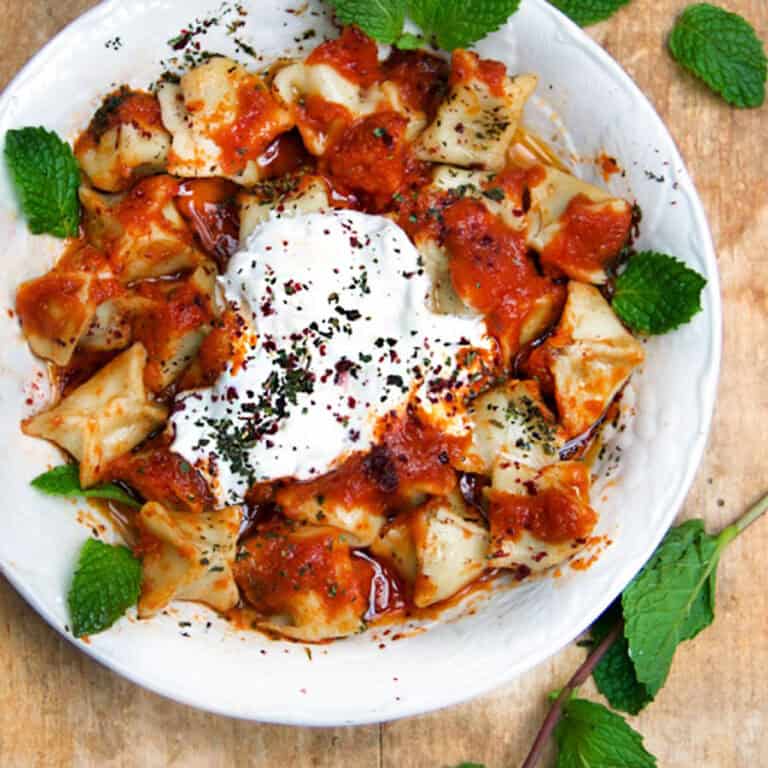 Tiny raviolis with tomato sauce, yogurt sauce and brown butter sauce and herbs.