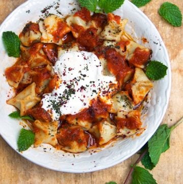 Turkish Manti is a dish for a special occasion: tiny lamb-stuffed dumplings topped with three sauces: caramelized tomato sauce, brown butter sauce, and garlicky yogurt sauce. This recipe shows you how to make authentic Turkish manti at home.