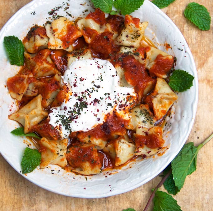 Turkish Manti is a dish for a special occasion: tiny lamb-stuffed dumplings topped with three sauces: caramelized tomato sauce, brown butter sauce, and garlicky yogurt sauce. This recipe shows you how to make authentic Turkish manti at home.